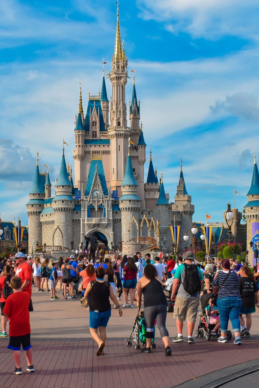 guests at Disney World walk in front of Cinderella's Castle at the Magic Kingdom