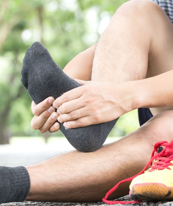 a man rubs his socked foot after removing his shoes