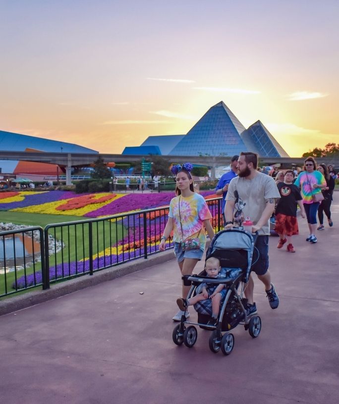 a man and woman visit disney with a toddler in a stroller
