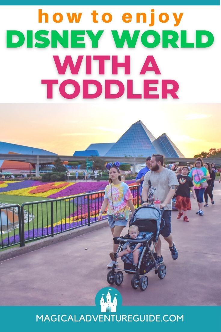 a man and woman walk in Epcot, at Disney with toddler in a stroller