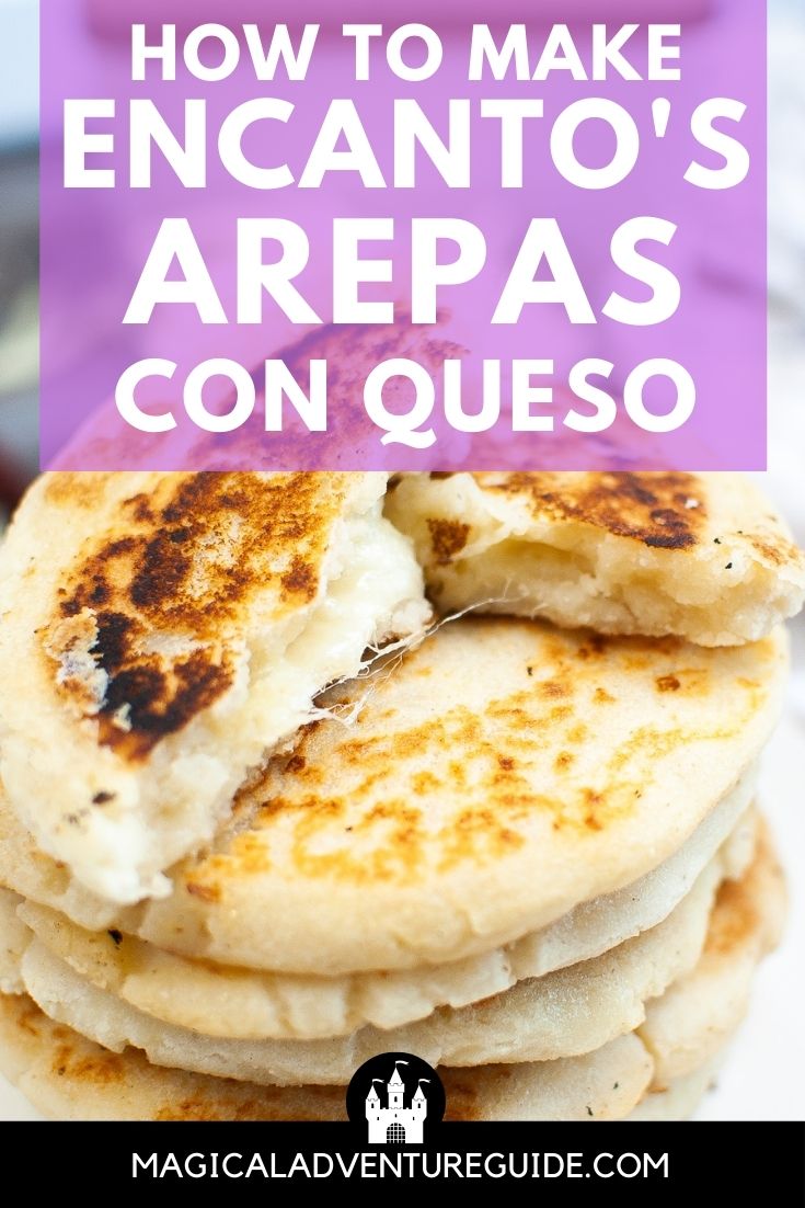 a stack of arepas con queso, with the top arepa broken open to show the cheesy middle