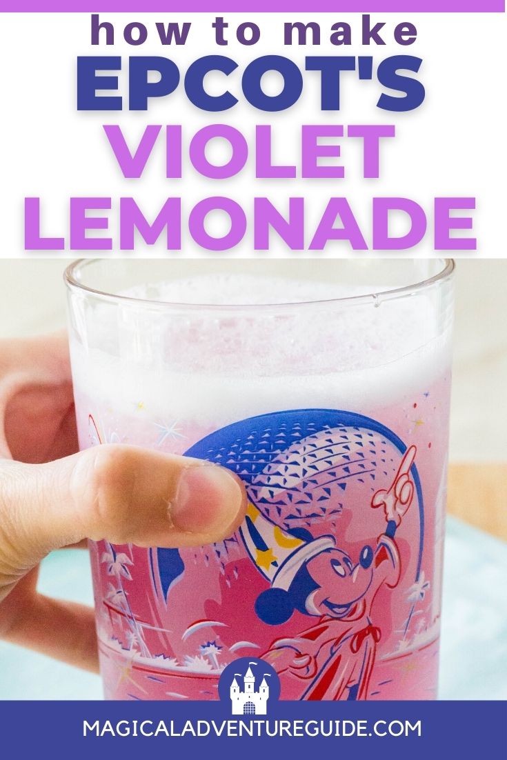 a woman's hand holds a commemorative Epcot glass full of violet lemonade
