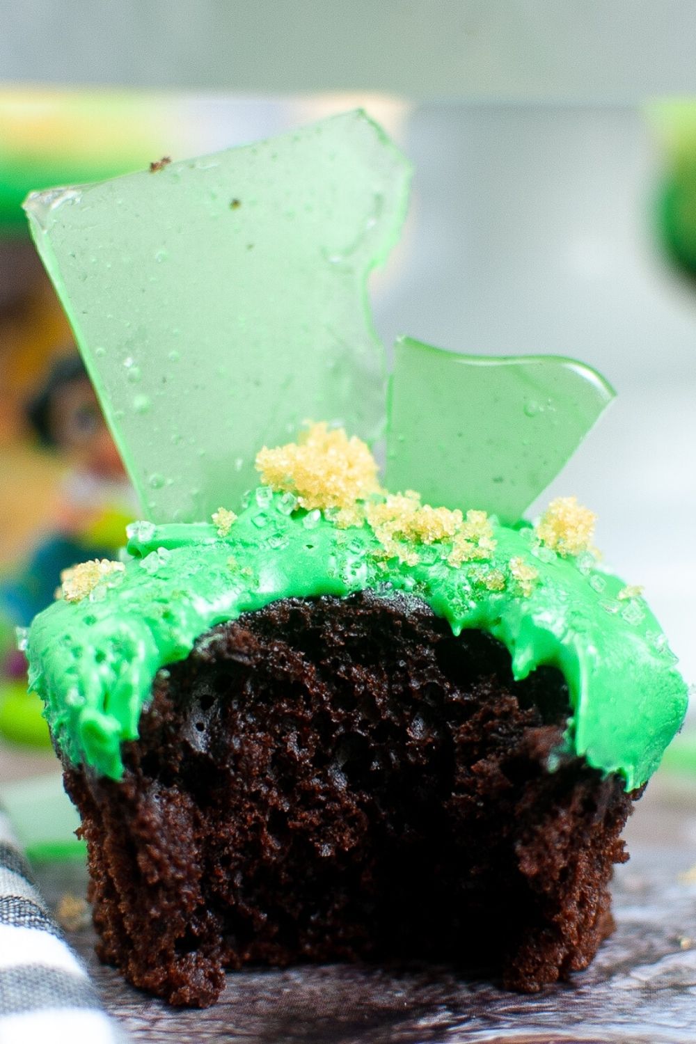 bruno cupcake for an encanto birthday party, showing green frosting, green candy glass from bruno's visions, and brown sugar sand