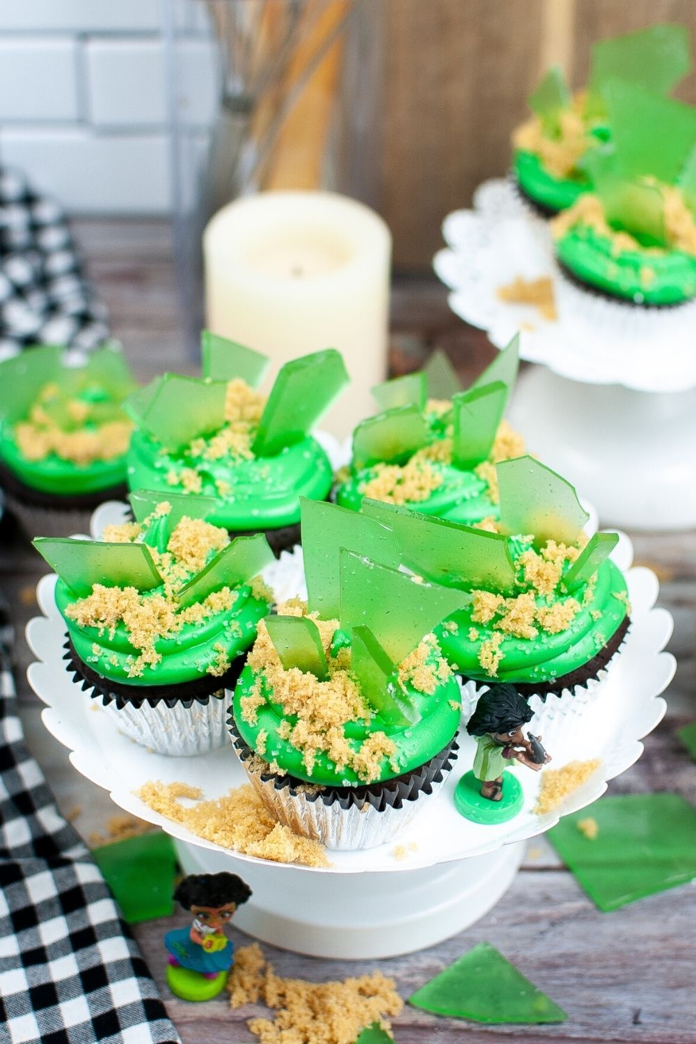 overhead view of a few Encanto birthday cupcakes on a white cake stand, with figurines of Mirabel and Bruno next to them.