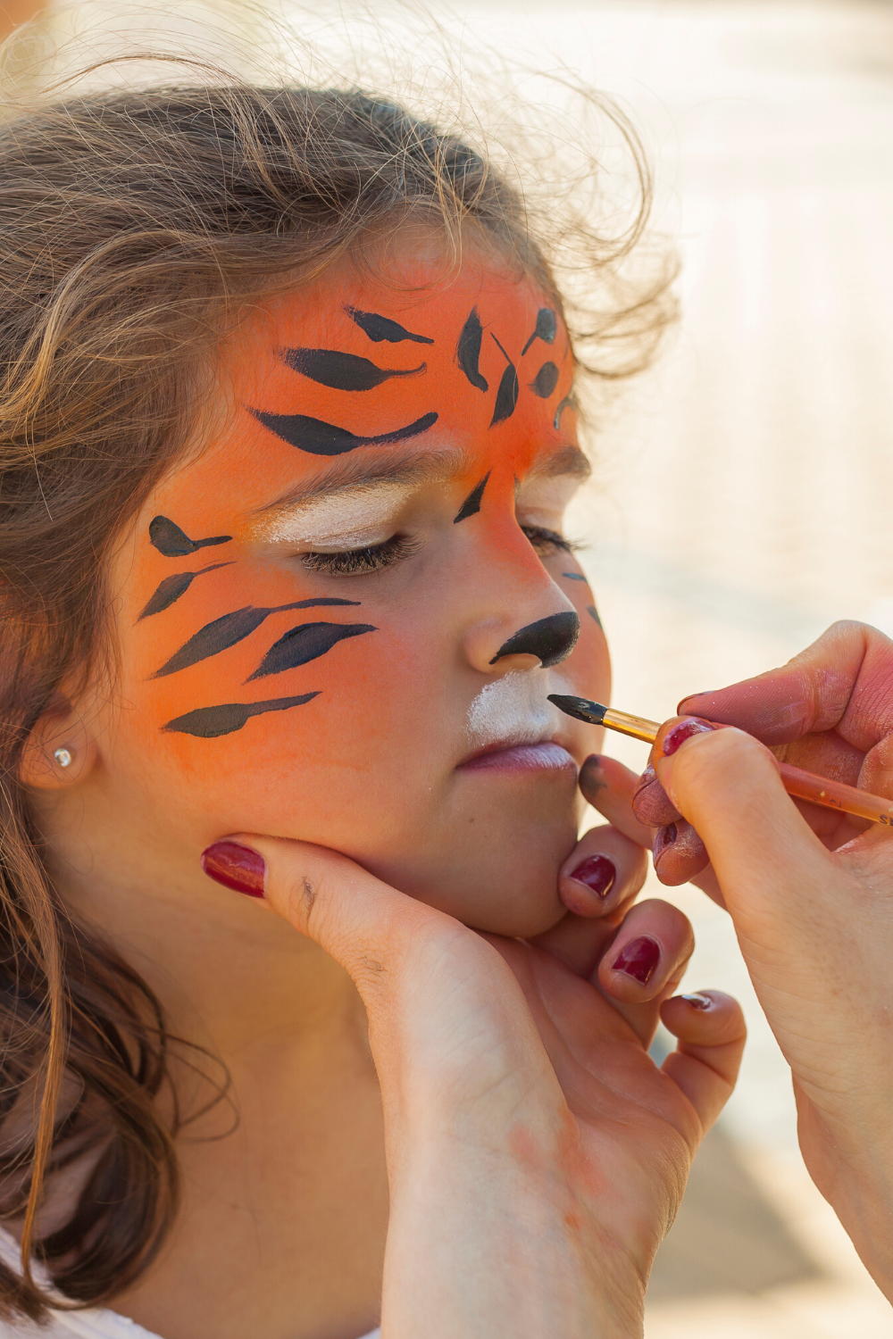 child getting their face painted in a tiger design