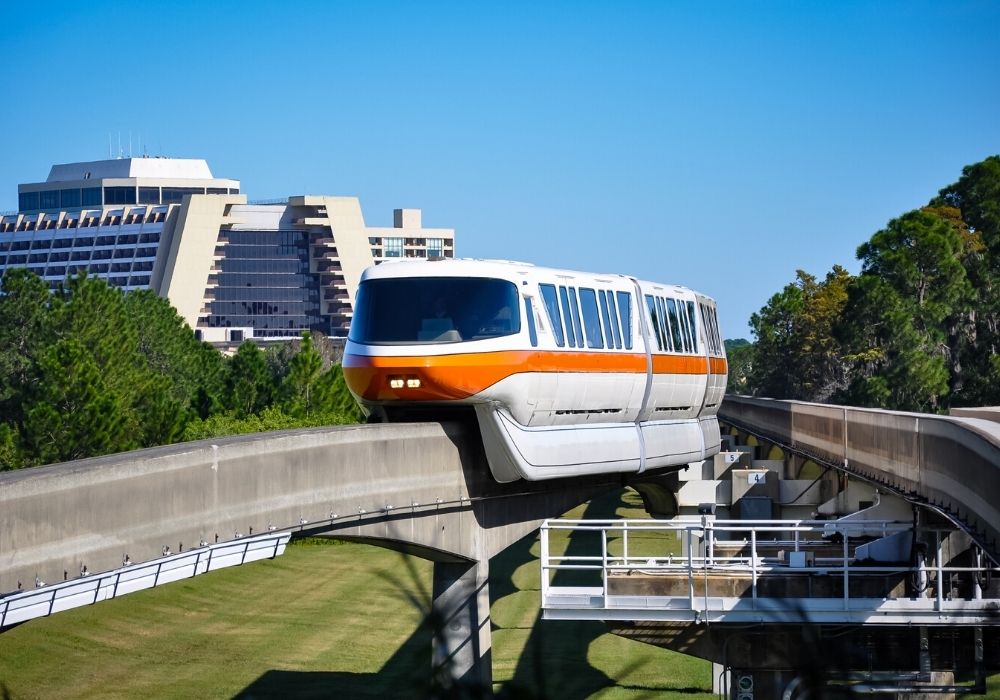 the orange train of the Disney Monorail passes by the outside of the Contemporary Resort at Walt Disney World