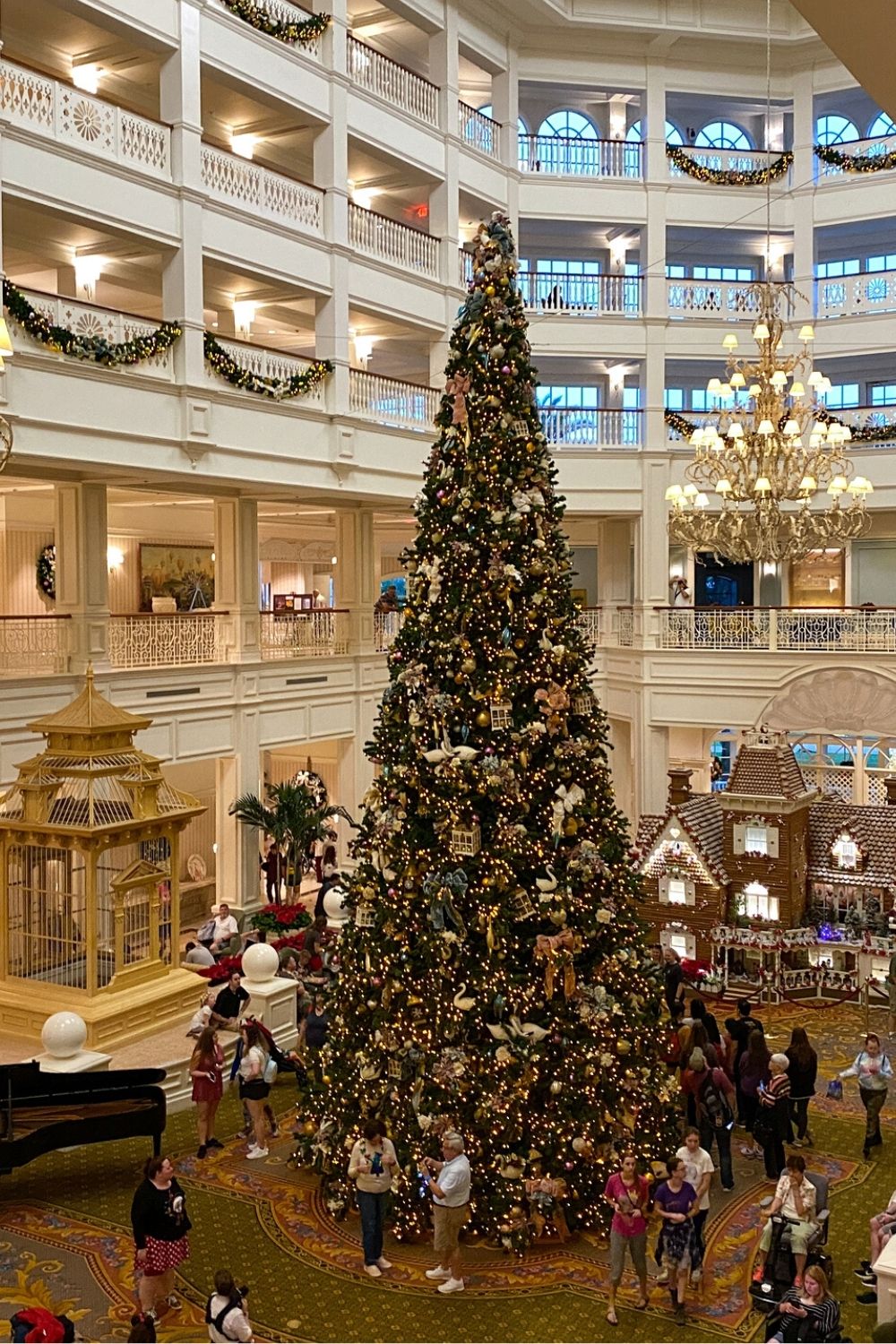 interior of Disney's Grand Floridian Resort at Christmas time, with a large Christmas tree in the center and a giant gingerbread house in the background.