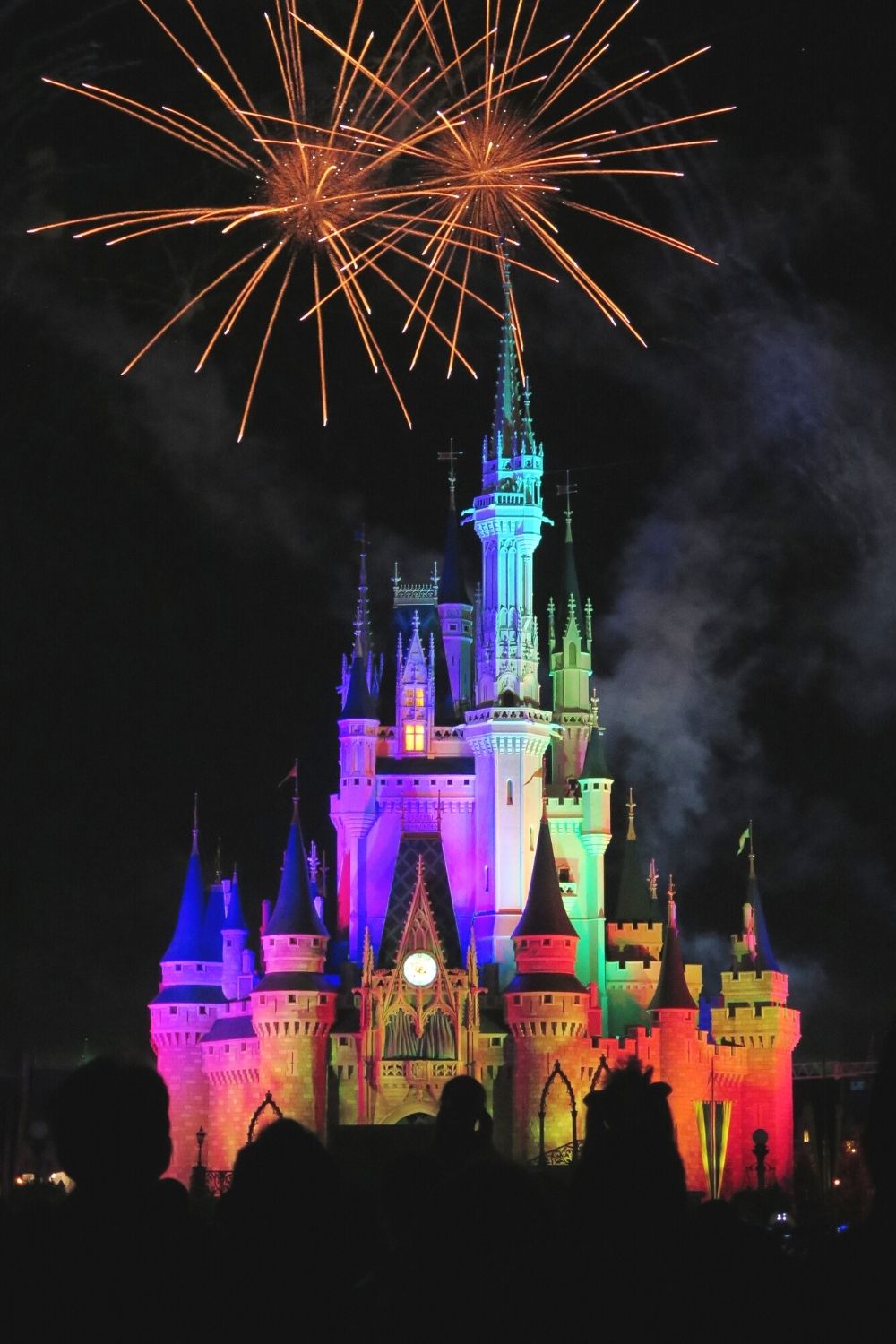 Cinderella's Castle lit up at night in Disney World, with fireworks overhead