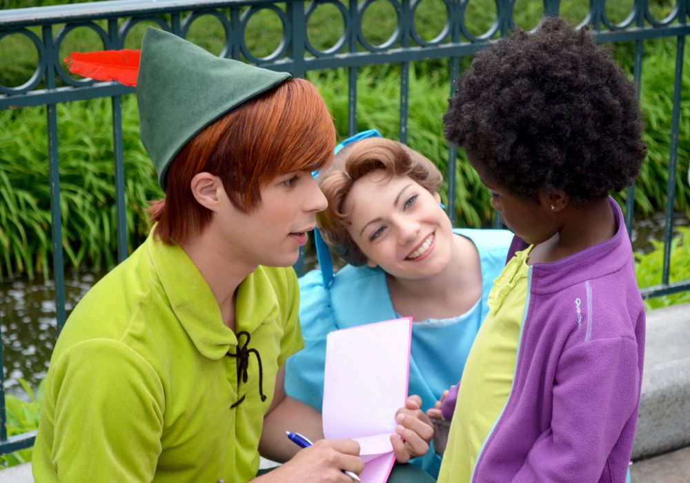 Peter Pan and Wendy sign a young girl's autograph book at Disney World