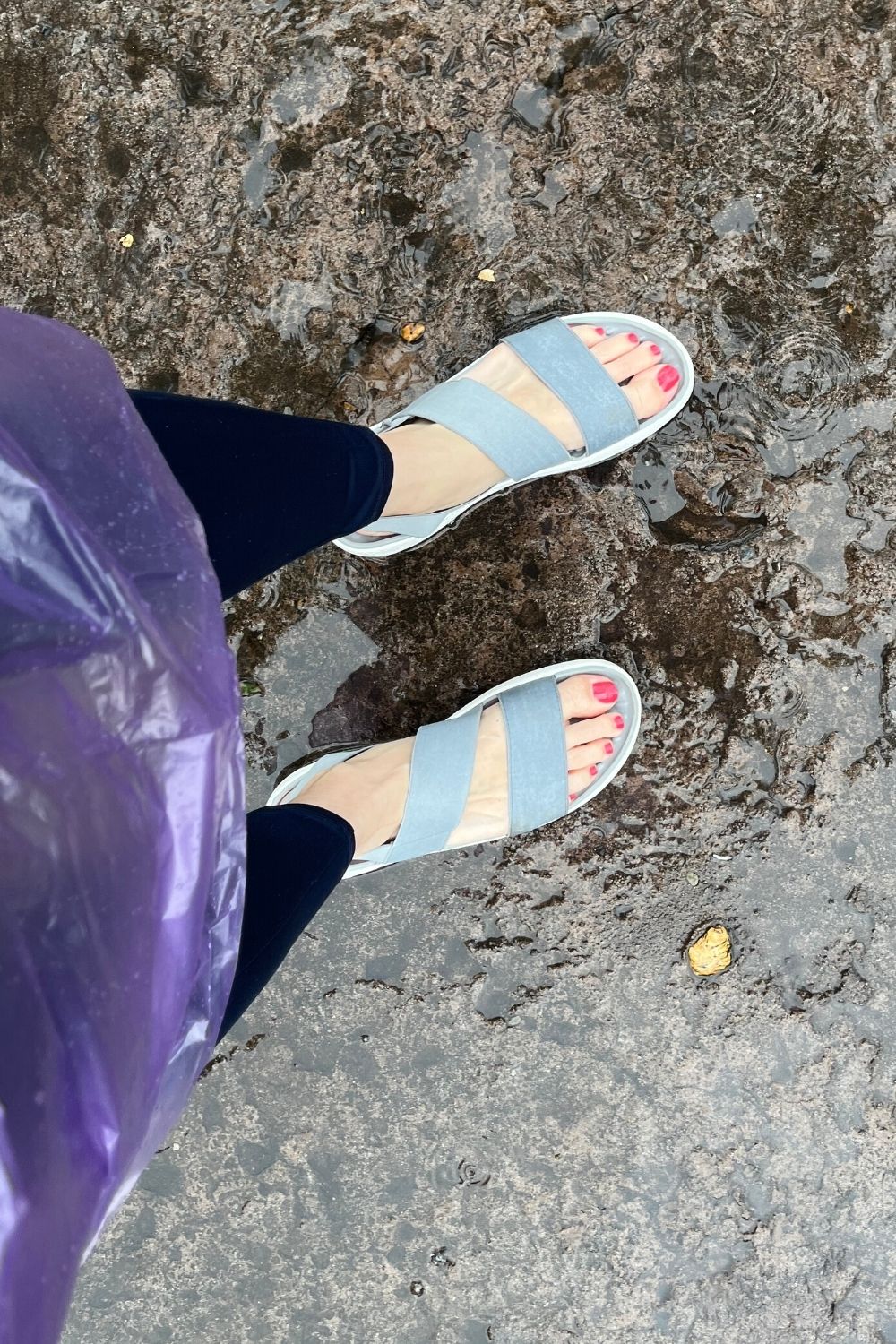 a woman's feet wearing Crocs sandals in Epcot on a rainy day